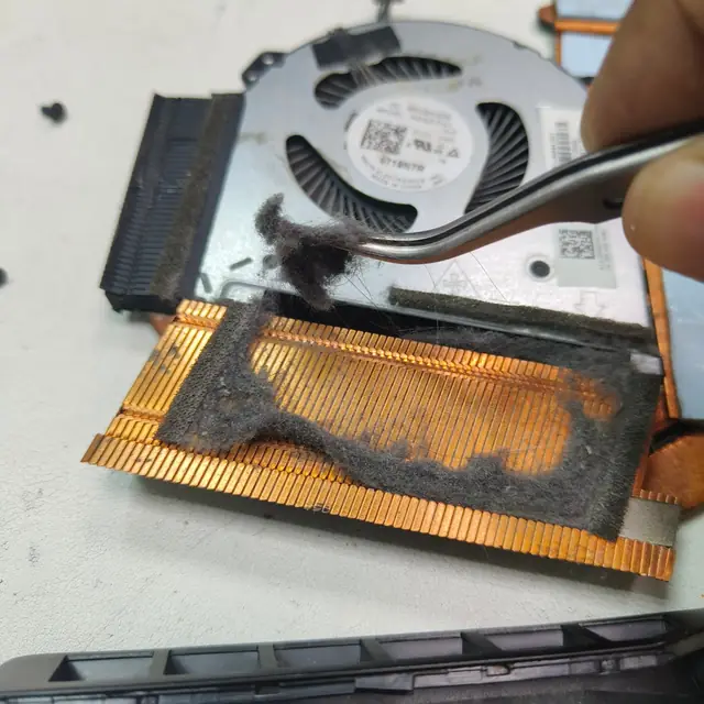 Removing dust from laptop fan and heatsink fins with tweezers