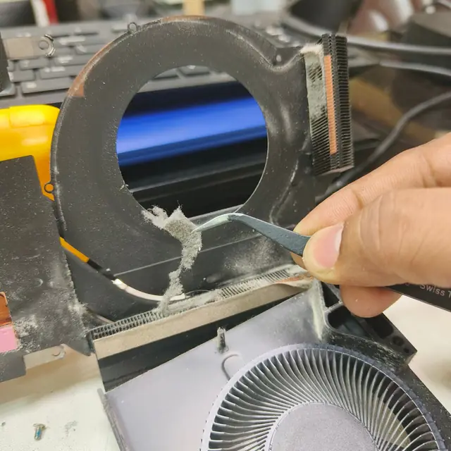 Removing dust from laptop heatsink with tweezers step 1