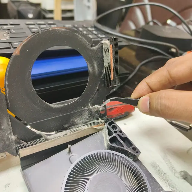 Removing dust from laptop heatsink with tweezers step 2