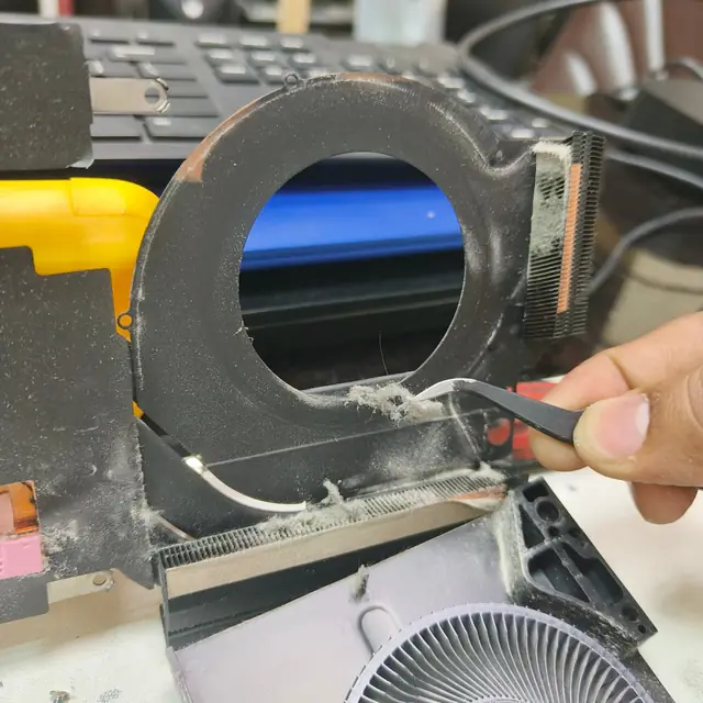 Removing dust from laptop heatsink with tweezers step 3