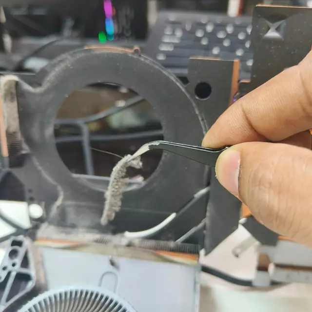 Removing lint from laptop heatsink fins with tweezers